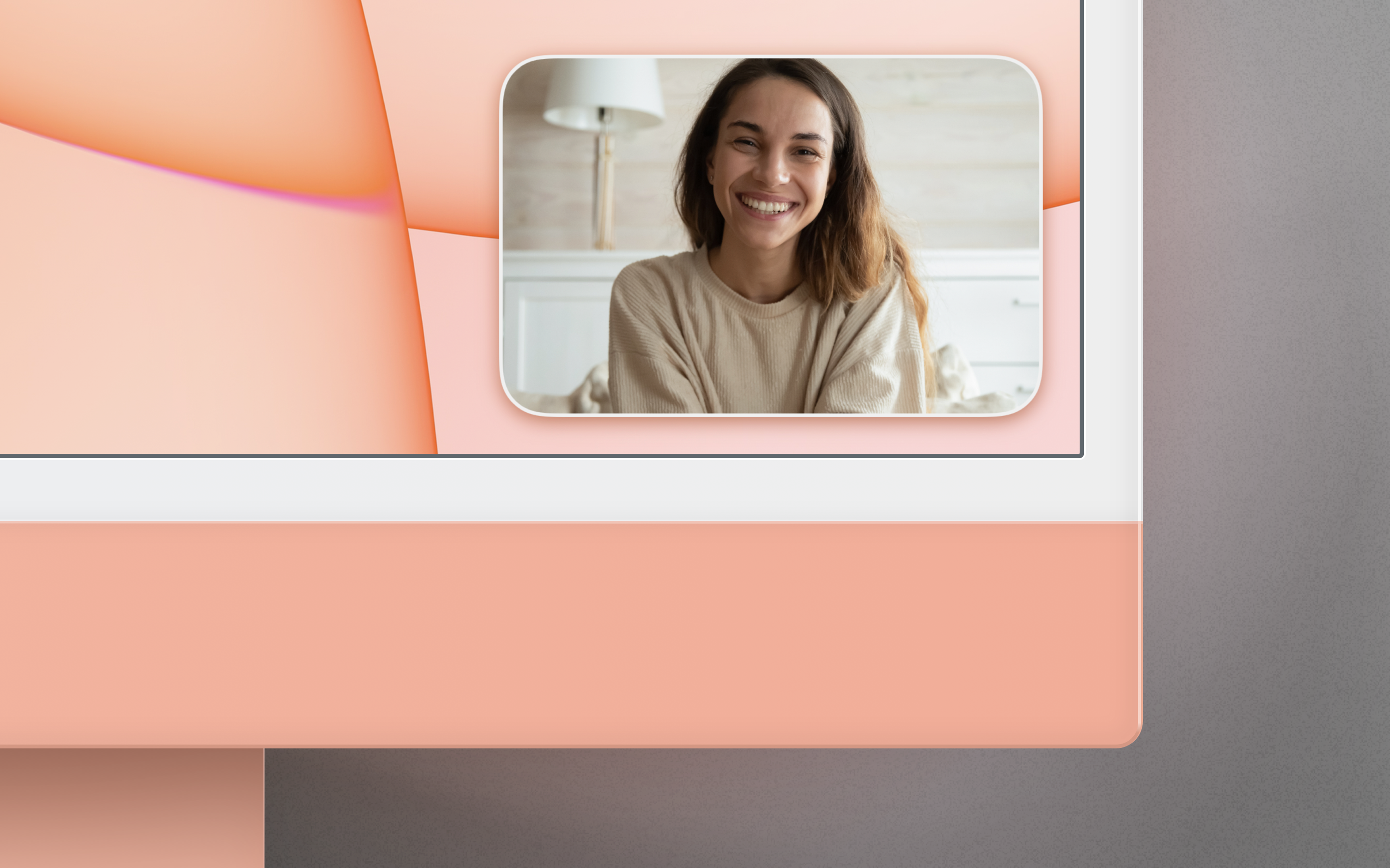The bottom right corner of an orange iMac, with Mirror Magnet running, which displays a camera image of a young woman.